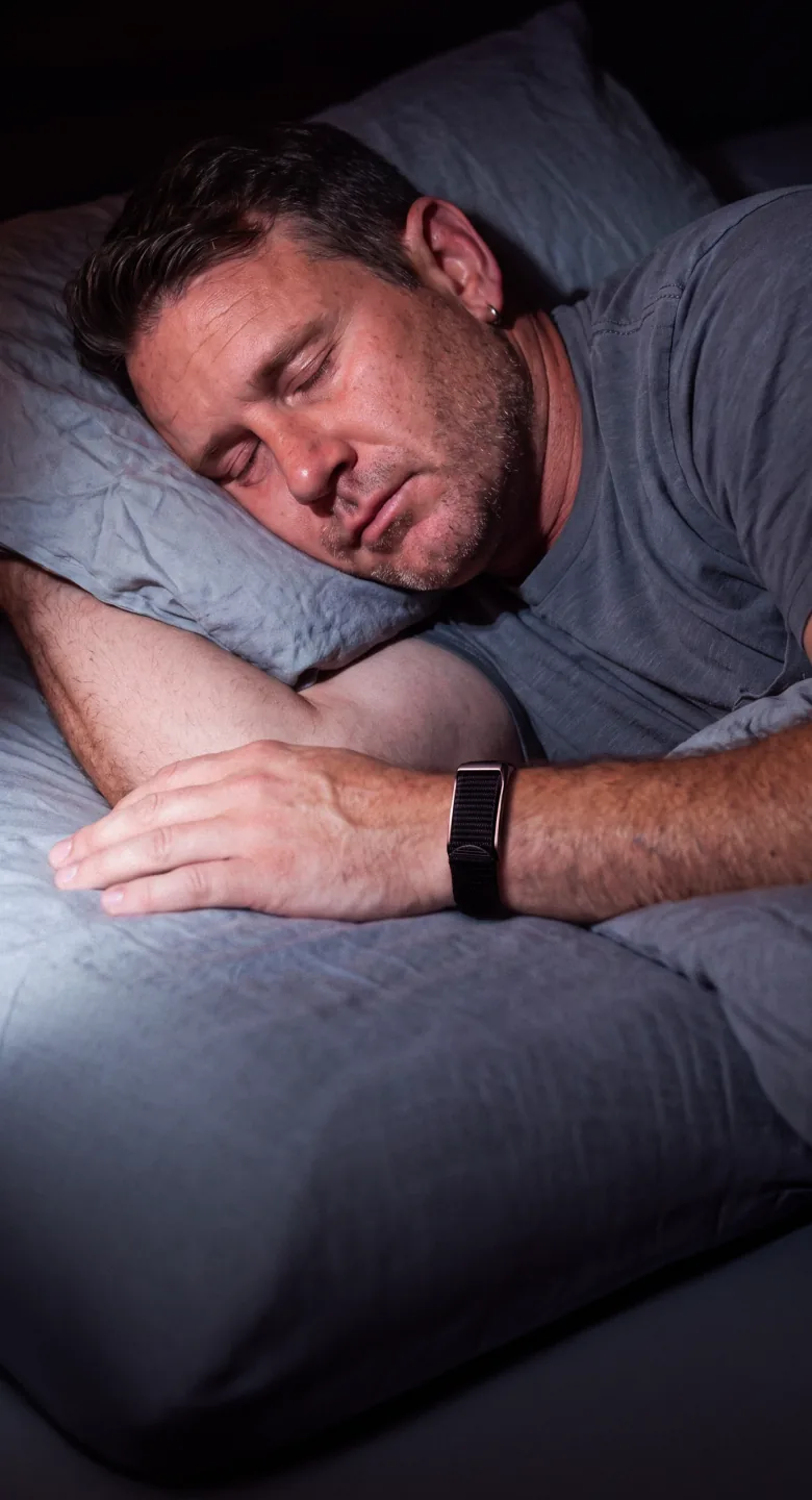 A man asleep on his side wearing the HLTH Band on his wrist