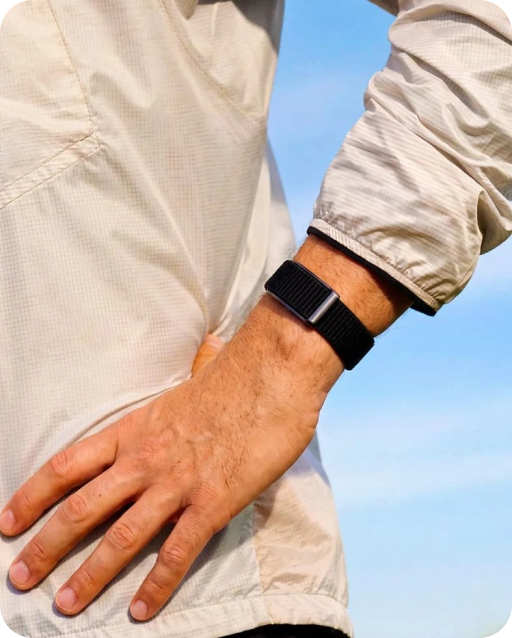 Man with his hand on his hip wearing the HLTH Band below a pale jacket cuff
