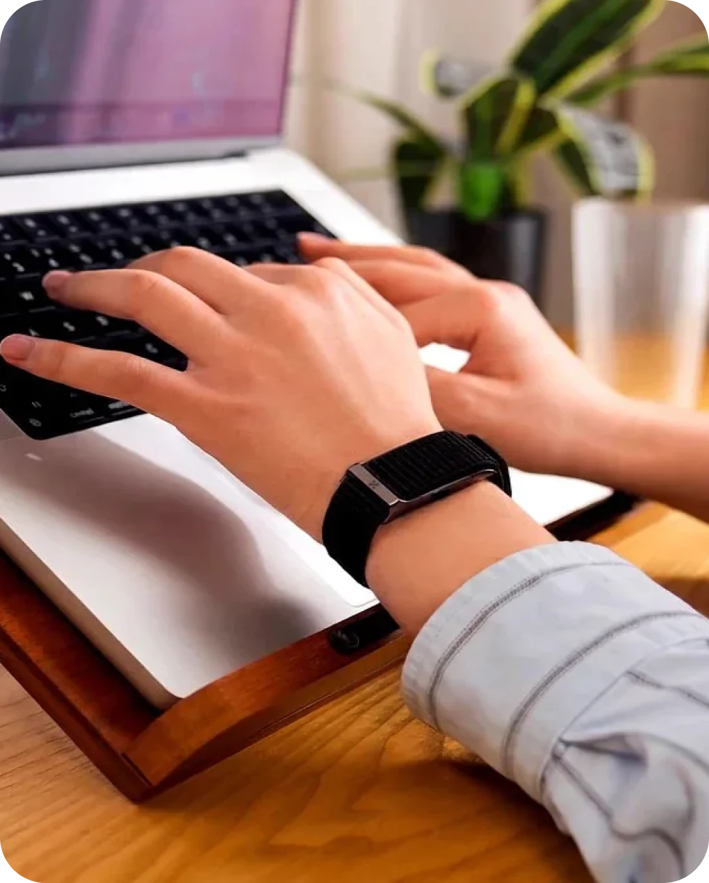 Hands typing on a laptop with the HLTH Band on the wrist