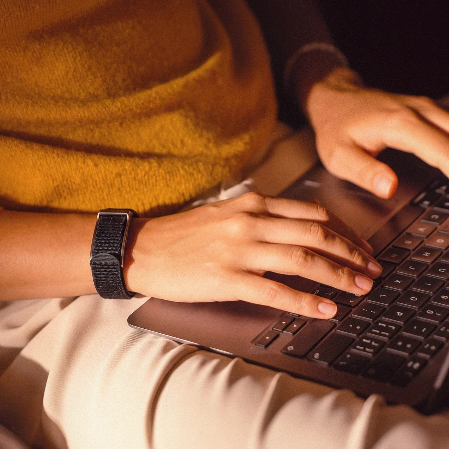 Sarah at her desk during the working day, wearing the HLTH Band